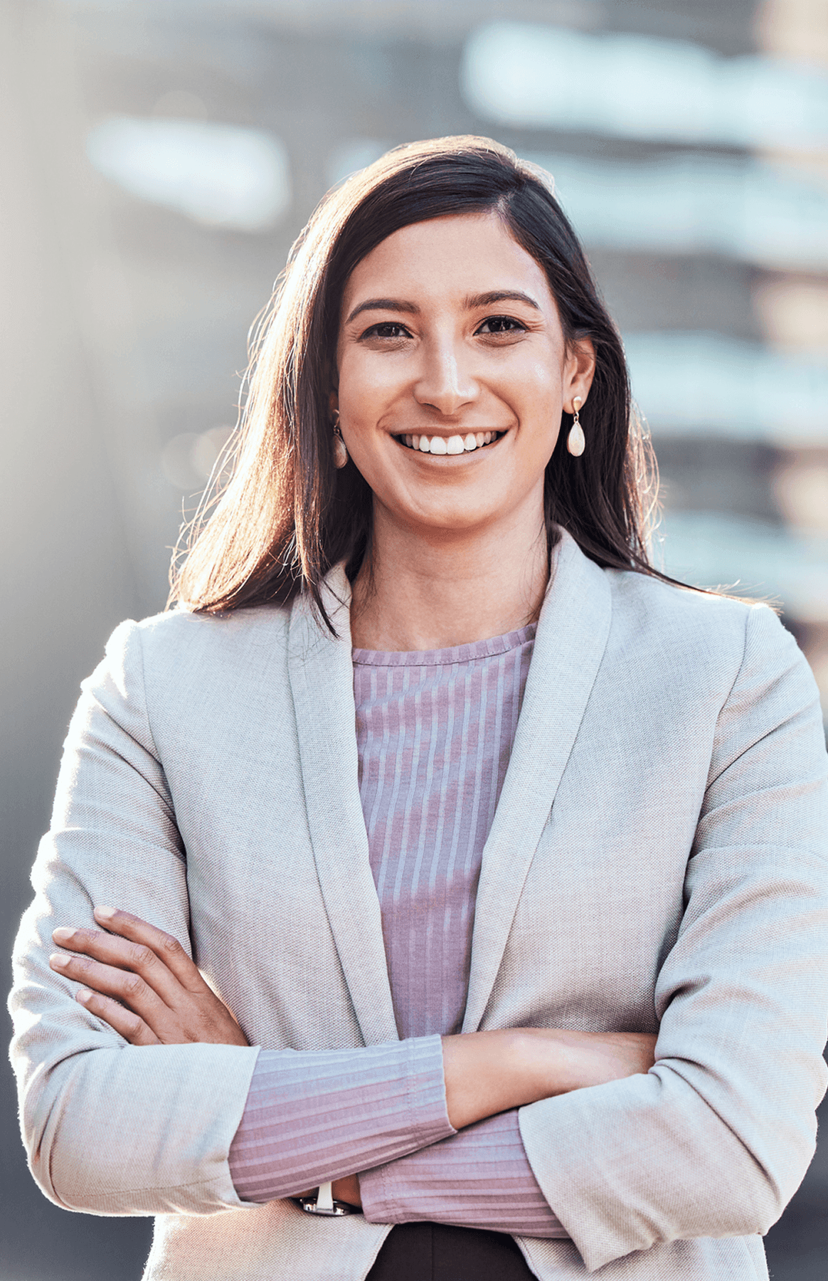 Smiling woman in blazer with crossed arms.