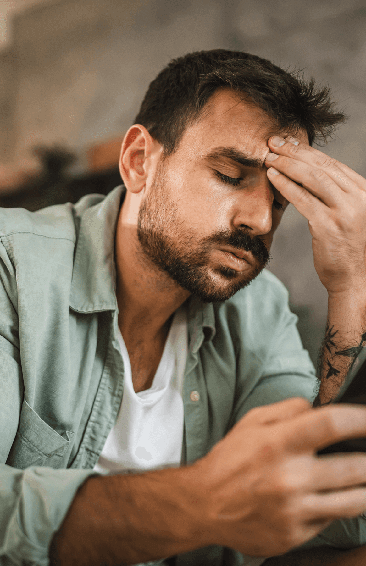Man looking stressed while holding smartphone.