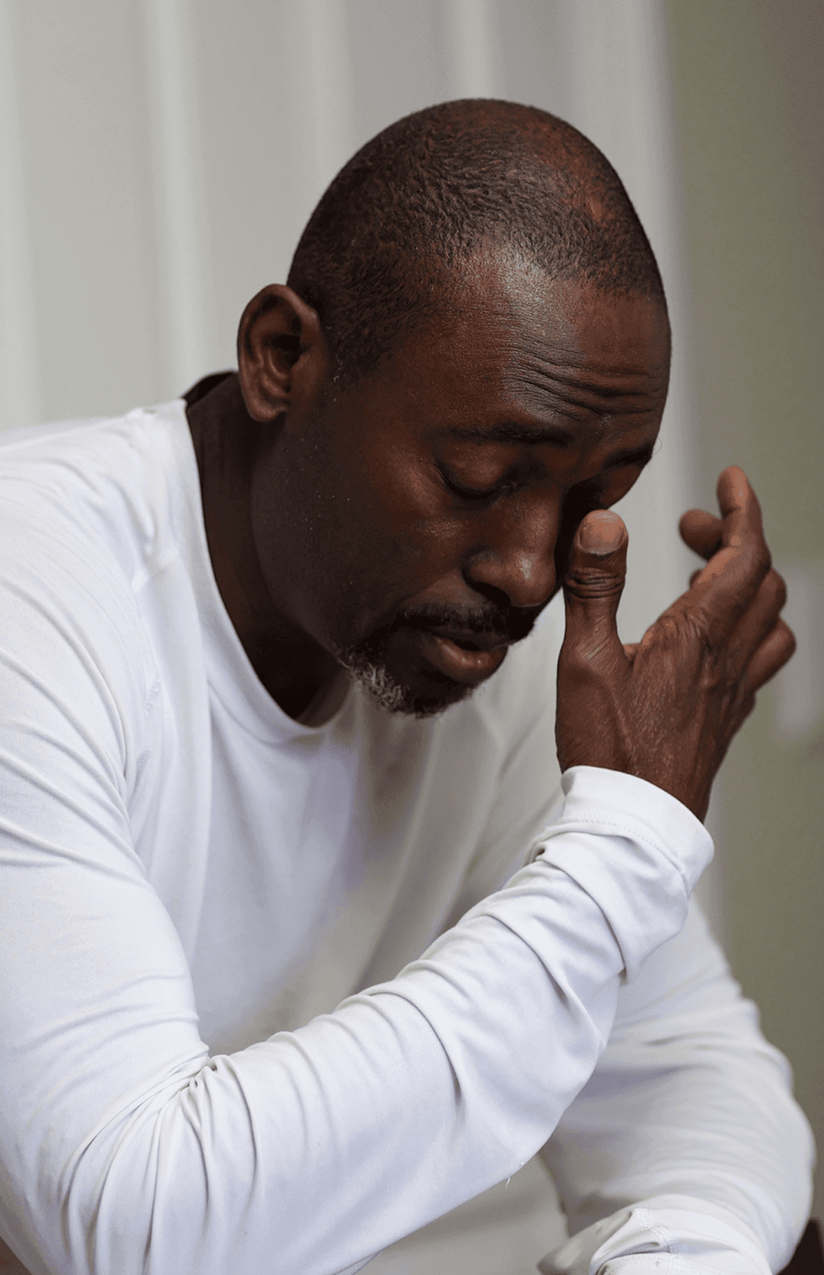 Man in white shirt rubbing his eyes.