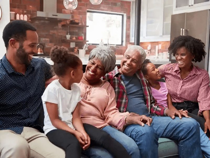 Family laughing together on living room sofa.